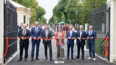 Gruppe formell gekleideter Personen durchschneidet ein rotes Band am offenen Engelstor in Wien-Hietzing.