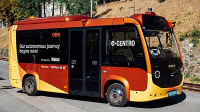 Orange-roter autonomer Elektrobus e-CENTRO von Otokar mit ÖBB-Branding auf einer Straße in Alpbach.