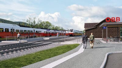 Rote und weiße Züge an einem modernisierten Bahnhof mit Personen auf dem Weg