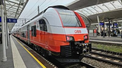 Roter und weißer ÖBB Regionalzug steht an einem Bahnsteig unter Glasdach