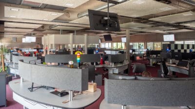 Innenansicht einer modernen Rettungsleitstelle mit Arbeitsplätzen, Monitoren und bunter Signalleuchte