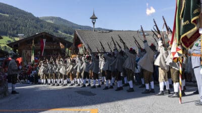 Schützen in Tracht schießen mit erhobenen Gewehren bei einer Veranstaltung in Alpbach.