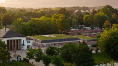 Hochwinkelansicht eines modernen Gebäudes mit grünem Dach in einer Parklandschaft mit Bergen im Hintergrund