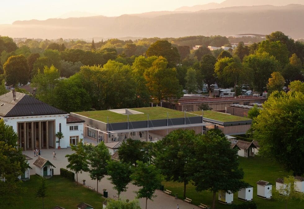 Hochwinkelansicht eines modernen Gebäudes mit grünem Dach in einer Parklandschaft mit Bergen im Hintergrund