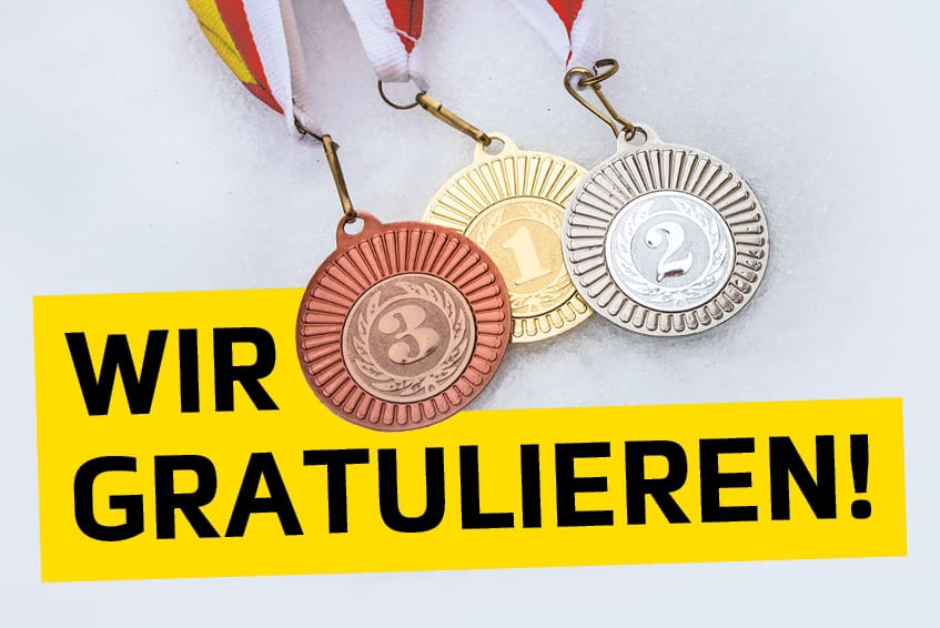 Drei Medaillen aus Bronze Gold und Silber neben einem gelben Banner mit der Aufschrift Wir gratulieren