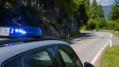 Polizeifahrzeug mit leuchtendem Blaulicht auf einer kurvigen Straße in den Bergen