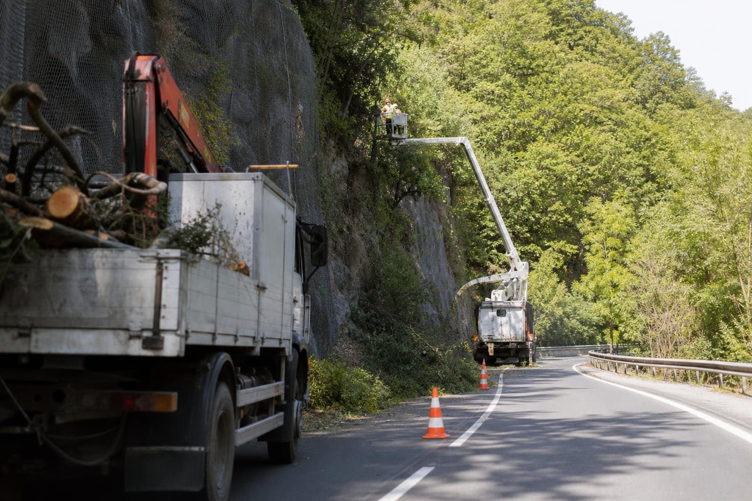 Lastwagen mit Kran und Hebebühne bei Holzarbeiten an einer Straße in der Weizklamm