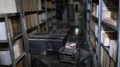 Verbrannter Computer und Etikettiergerät auf einem Tisch in einem Archiv mit Regalen