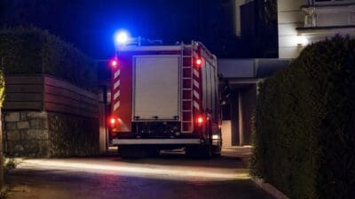 Rotes Feuerwehrfahrzeug von hinten mit rotem und blauem Blaulicht in der Nacht