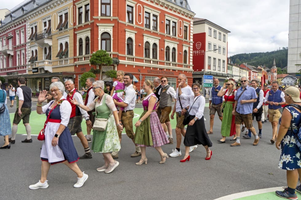 Menschen in traditionellen Trachten marschieren bei einem Festumzug durch die Innenstadt
