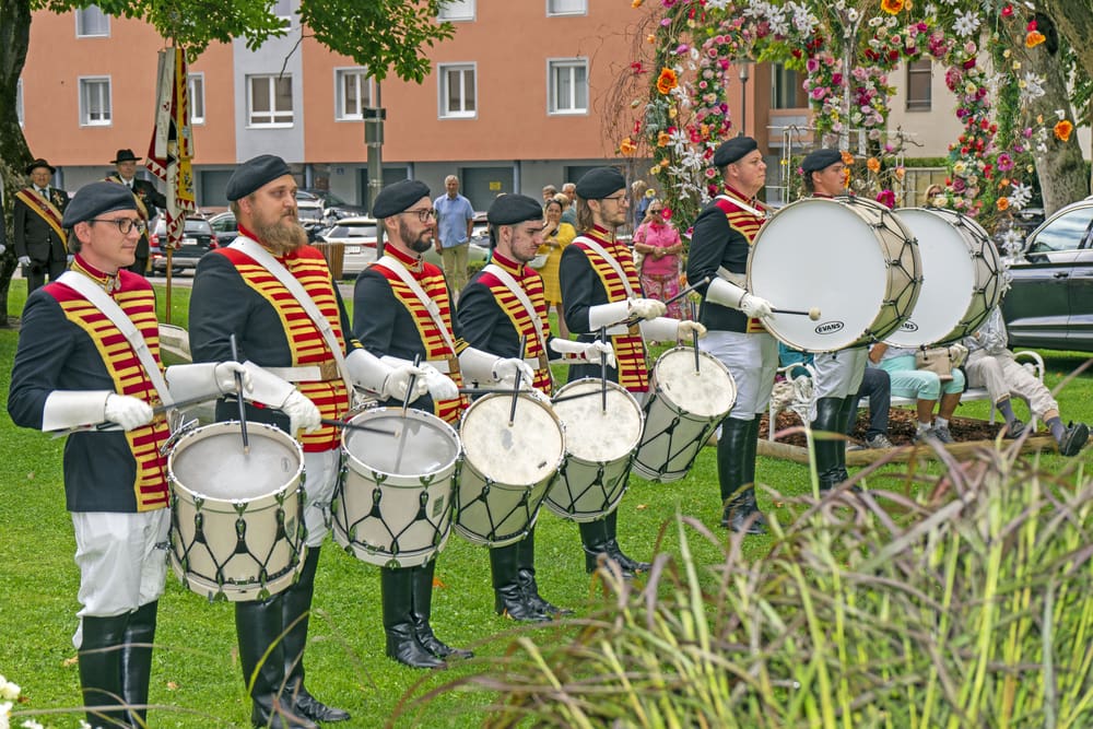Trommler in schwarzen Uniformen mit roten und gelben Bändern spielen Trommeln im Stadtpark