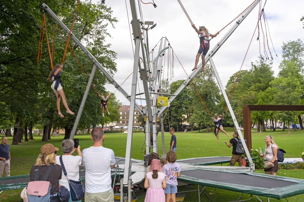 Zuschauer beobachten Personen auf einer großen mechanischen Schaukelanlage im Stadtpark.