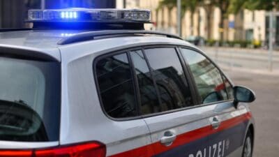 Silbernes Polizeifahrzeug mit aktiviertem blauem Blaulicht auf dem Dach