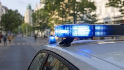 Blaues Blaulicht leuchtet auf dem Dach eines silbernen Polizeiautos in einer Wiener Straße