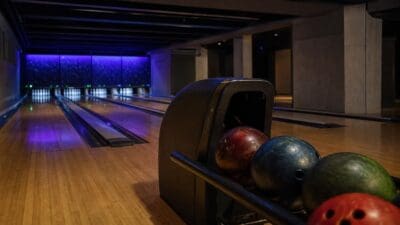 Bowlingkugeln in einem Rückführgerät vor leeren Bowlingbahnen mit blauer Beleuchtung