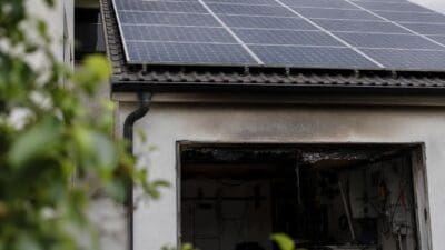 Photovoltaikanlage auf dem Dach einer Garage mit verrußtem und verkohltem Eingang