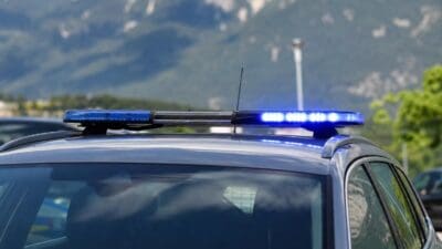 Blaues Blaulicht leuchtet auf dem Dach eines Polizeifahrzeugs vor Bergpanorama