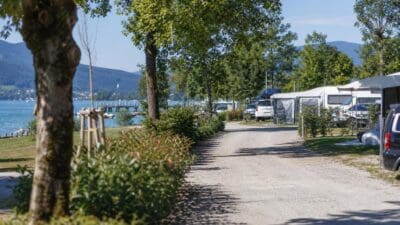 Ein Weg führt durch einen mit Wohnwagen bestückten Campingplatz am Ufer des Wörthersees.