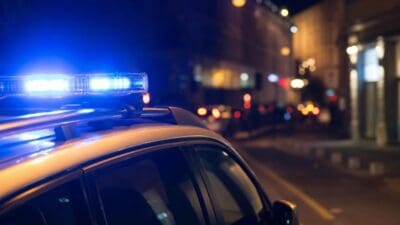 Nahaufnahme des Blaulichts auf dem Dach eines Polizeifahrzeugs in einer nächtlichen Umgebung