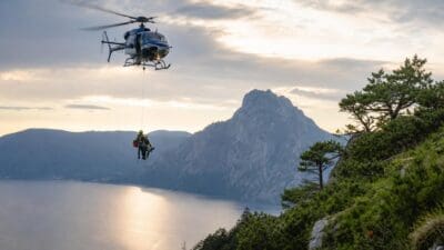 Polizeihubschrauber hievt Bergsteiger an einem Seil über dem Traunsee in die Luft