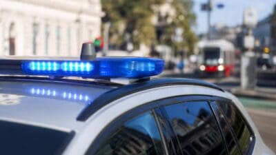 Blaues Blaulicht leuchtet auf dem Dach eines Polizeifahrzeugs in einer Wiener Straße