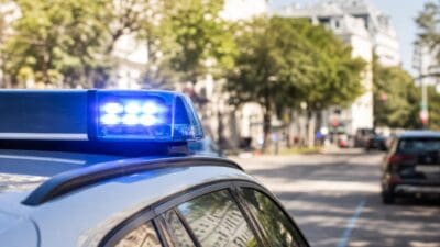 Blaues Blaulicht auf dem Dach eines Polizeifahrzeugs in einer urbanen Straße.