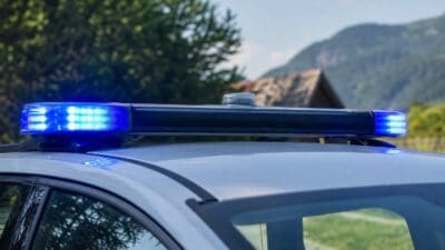 Nahaufnahme des Blaulichts auf dem Dach eines Polizeifahrzeugs mit Berglandschaft im Hintergrund