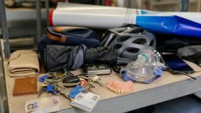 Auf einem Tisch sind mehrere Schlüssel, zwei Ausweise, ein künstliches Gebiss und eine Atemmaske zu sehen.