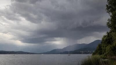Dunkle Wolken mit Regenschauern über einem See vor Bergpanorama in Kärnten