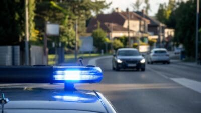 Blaues Blaulicht leuchtet auf dem Dach eines Polizeifahrzeugs in einer Wohngegend.