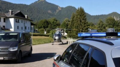 Polizeifahrzeuge mit Blaulicht und Rettungshubschrauber vor Bergkulisse
