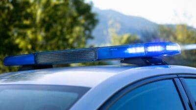 Nahaufnahme eines aktivierten blauen Blinklichts auf einem weißen Einsatzfahrzeug mit Bergen im Hintergrund