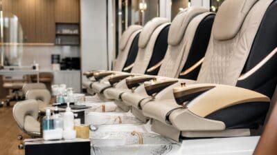 Reihe von beigen und schwarzen Pedikürestühlen mit Waschbecken in einem modernen Nagelstudio