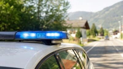 Blaues Blaulicht auf einem weißen Einsatzfahrzeug an einer Straße mit Bergpanorama