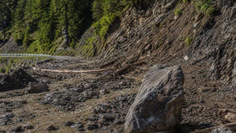 Großer Felsbrocken in Schlamm und Geröll auf der Straße nach Murenabgang bei Pfafflar