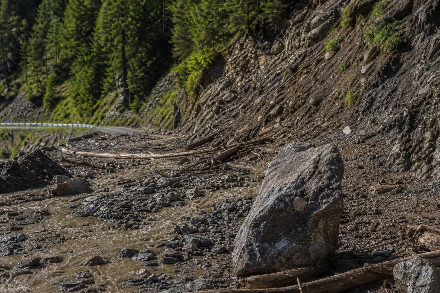 Großer Felsbrocken in Schlamm und Geröll auf der Straße nach Murenabgang bei Pfafflar