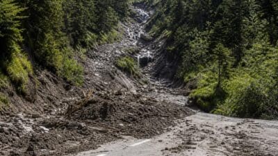 Mit Schlamm und Geröll bedeckte Straße auf der L 246 nach Murenabgängen.