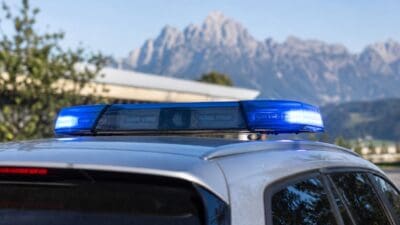 Blaues Blaulicht auf dem Dach eines silbernen Autos mit Bergen im Hintergrund