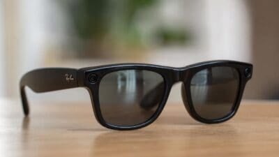 Eine schwarze Ray-Ban Meta Smart-Brille mit integrierten Kameras liegt auf einem Holztisch.