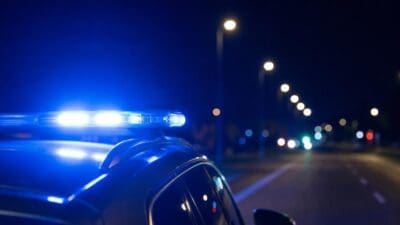 Blaues Blaulicht auf dem Dach eines Polizeiautos bei Nacht auf einer Straße
