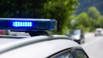 Blaues Blaulicht auf dem Dach eines weißen Einsatzfahrzeugs an einer Straße