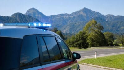 Seitenansicht eines Polizeifahrzeugs mit blauem Blaulicht vor einer Berglandschaft