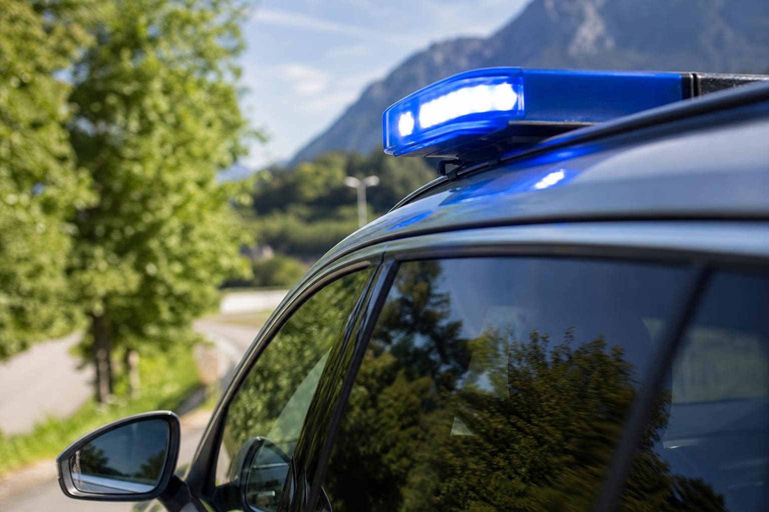 Blaues Blaulicht leuchtet auf dem Dach eines Einsatzfahrzeugs vor Berglandschaft
