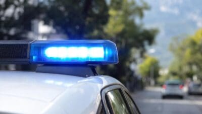 Blaues Blaulicht leuchtet auf dem Dach eines weißen Polizeifahrzeugs.