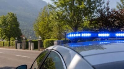 Polizeifahrzeug mit eingeschaltetem Blaulicht auf einer Straße in bergiger Umgebung