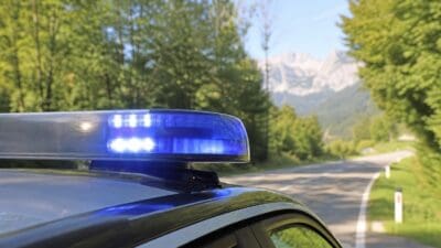 Aktiviertes blaues Blaulicht auf einem Polizeifahrzeug an einer Landstraße mit Bergen im Hintergrund