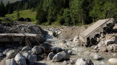 Zerstörte Betonbrücke liegt im reißenden Fluss mit Felsbrocken und Trümmern im Valsertal