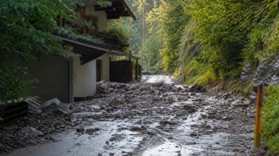 Mit Steinen und Schlamm bedeckte Straße vor einem Haus in der Kundler Klamm