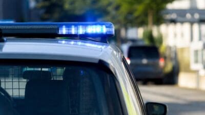 Nahaufnahme des blauen Blaulichts auf dem Dach eines weißen Polizeifahrzeugs.