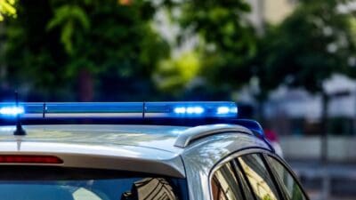 Nahaufnahme des blauen Blaulichts auf dem Dach eines silbernen Polizeifahrzeugs mit unscharfem Hintergrund